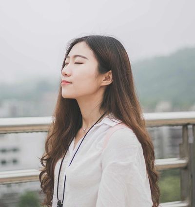 woman closing eyes white standing against stainless steel rail
